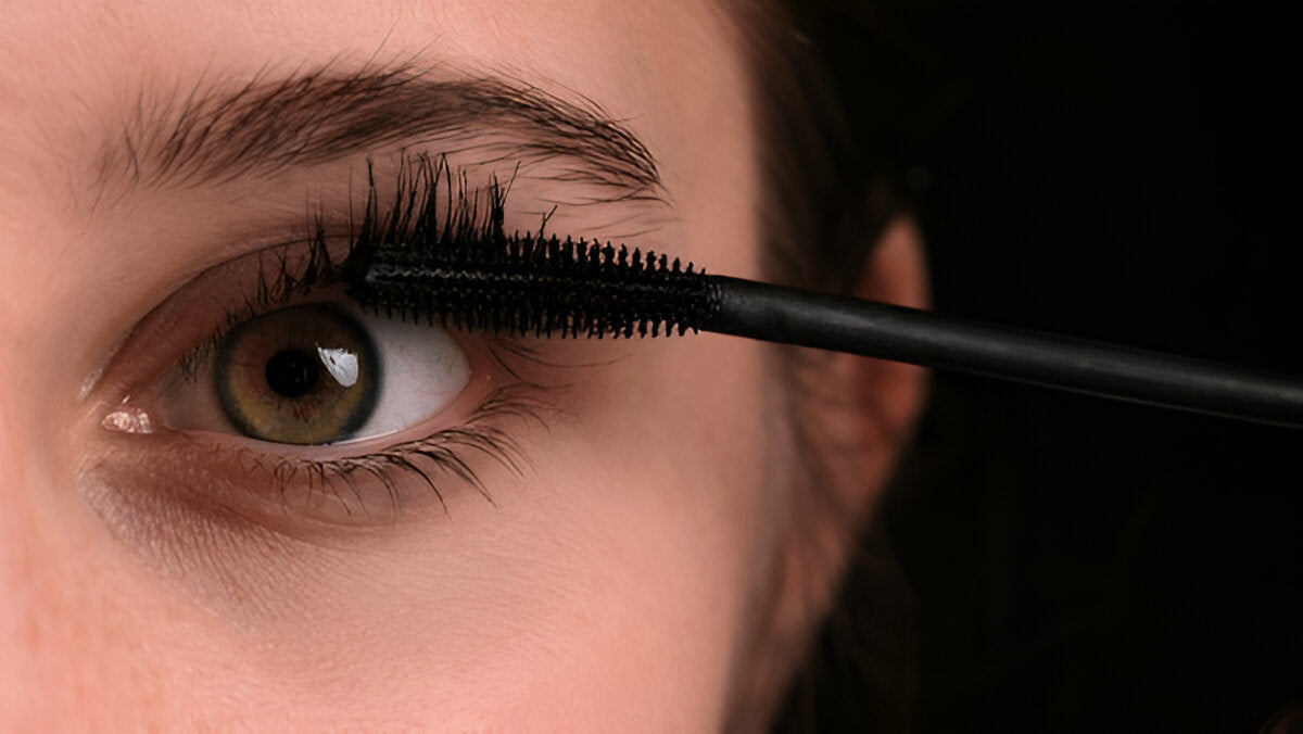 Close-up of a black mascara wand applying mascara to upper eyelashes